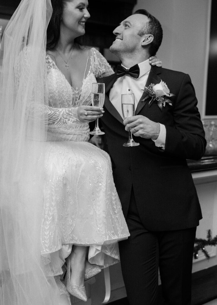 Black and white portrait of a bride and groom with champagne glasses at Flourtown Country Club