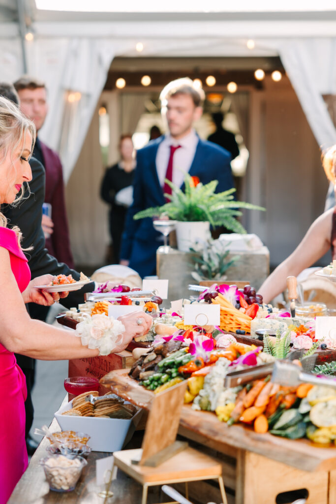 Wedding guests filling up plates at a grazing table during cocktail hour at Flourtown Country Club
