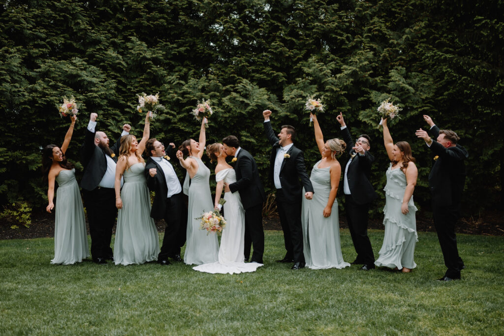 Wedding party celebrating the bride and groom sharing a kiss at Flourtown Country Club