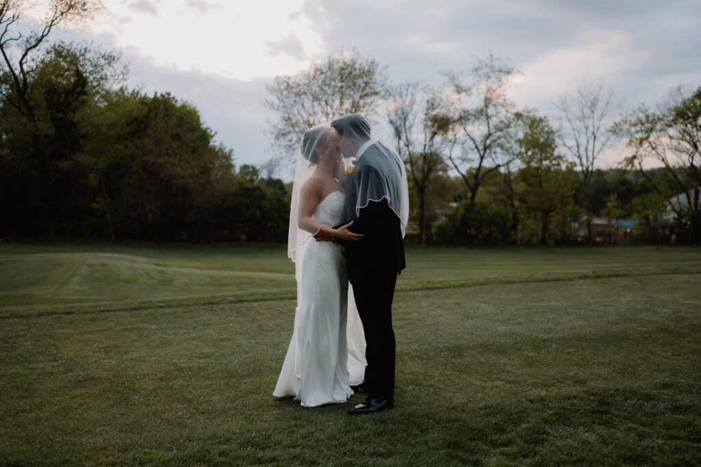 Bride and groom portrait underneath wedding veil on the golf course at Flourtown Country Club
